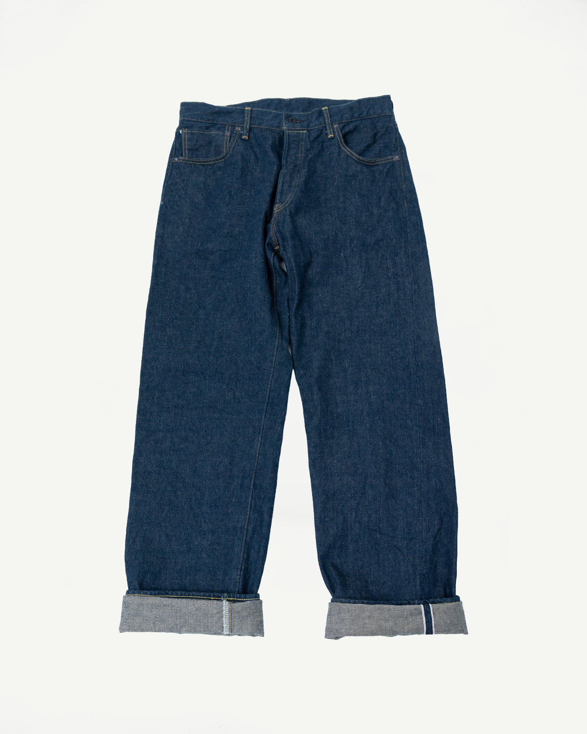 Flat lay of selvedge denim jeans, front view, loose straight fit, cuffed hem detail visible