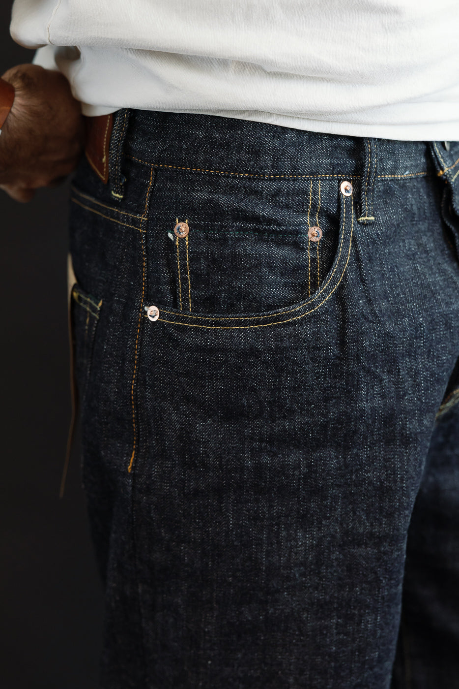 Close-up front view of dark selvedge denim jeans on male model, 5'9