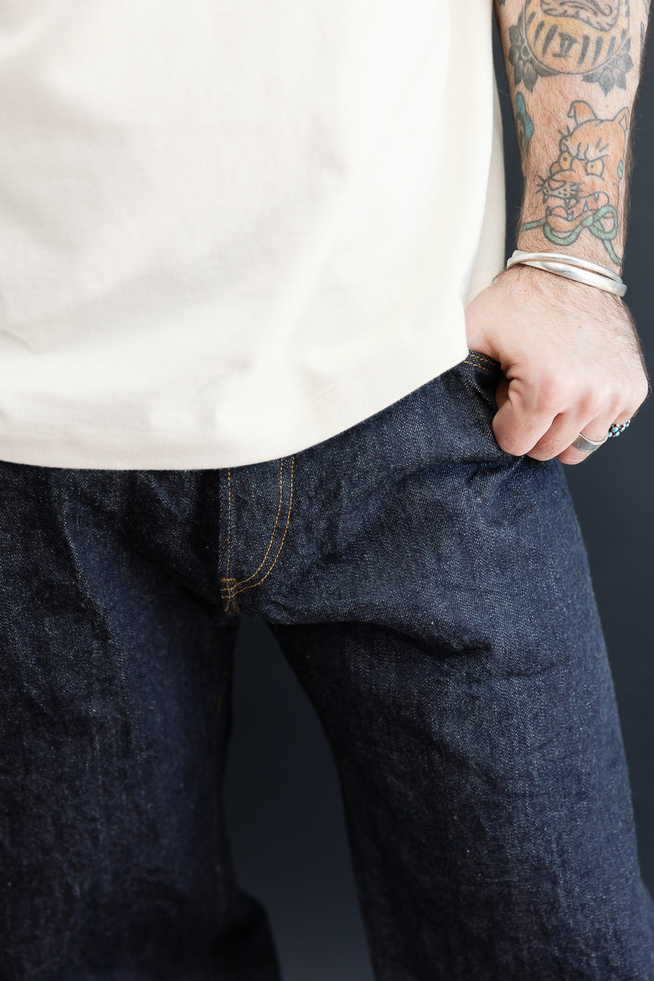 Close-up front view of dark indigo selvedge denim jeans on a male model, 5'9