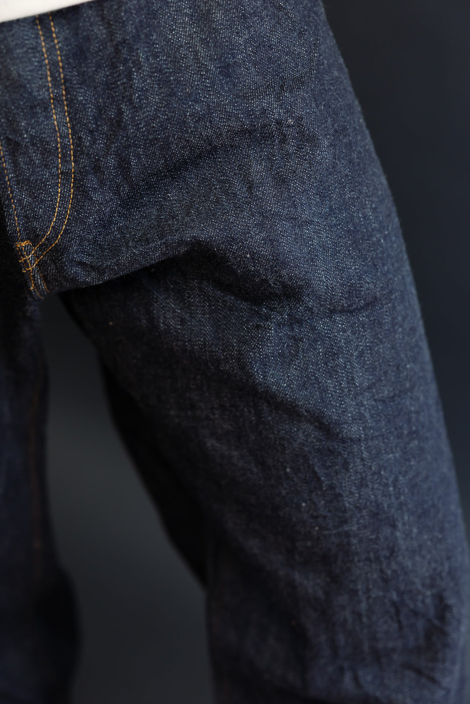 Close-up of the front thigh and seam of dark indigo selvedge denim jeans.