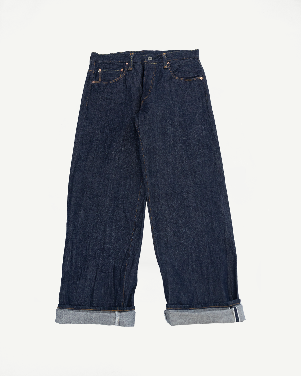 Front view flat lay of dark indigo wide-leg selvedge denim jeans with cuffed hems.