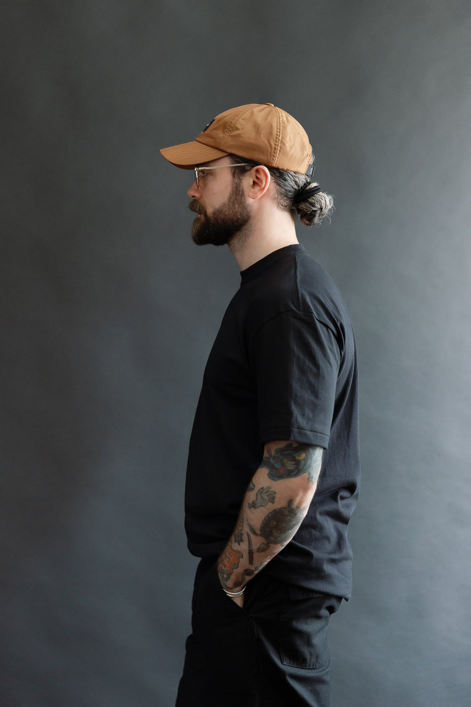 Male model 5'9 165lbs athletic build wearing black t-shirt, left side view, waist up