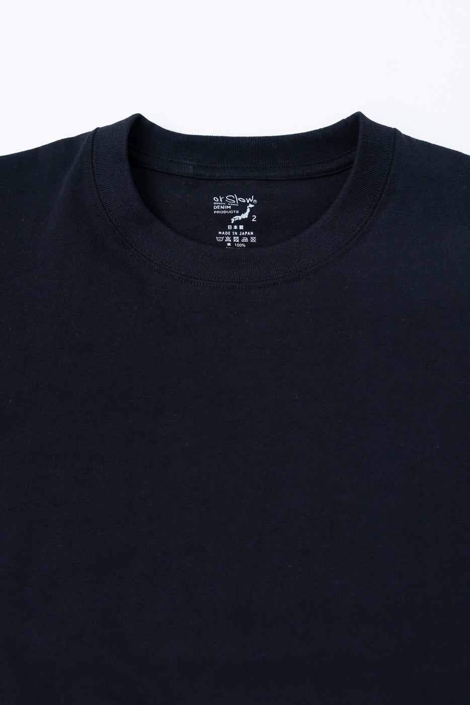 Close-up of black t-shirt front upper chest, showing crew neck collar, tag, and fabric texture.