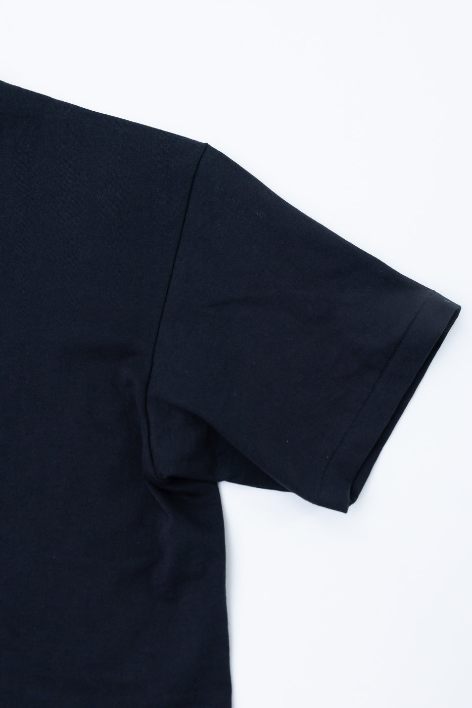 Close-up of black short sleeve t-shirt right side, showing sleeve hem and fabric texture.