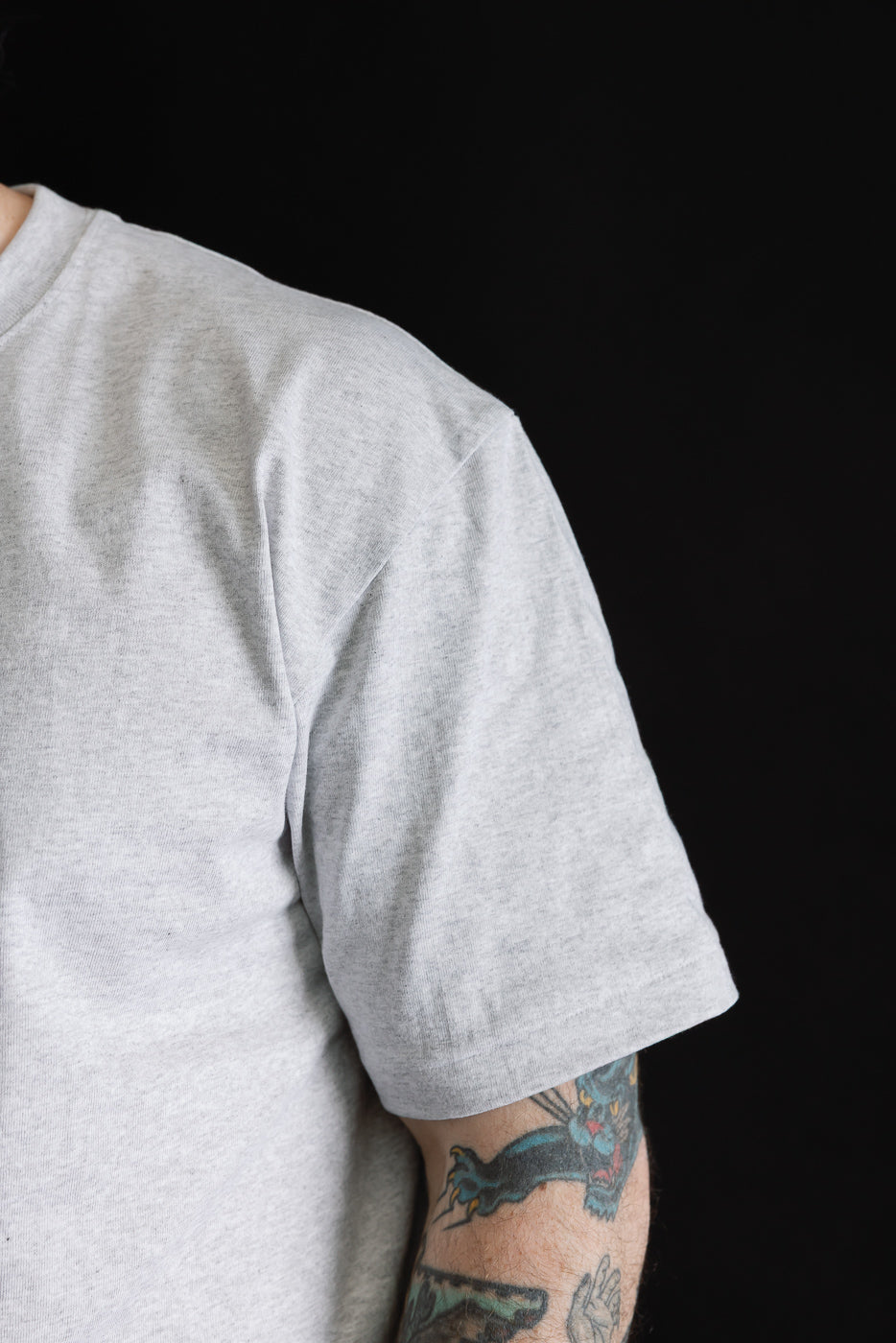 Close-up of right side sleeve and shoulder of heather grey T-shirt on 5'9