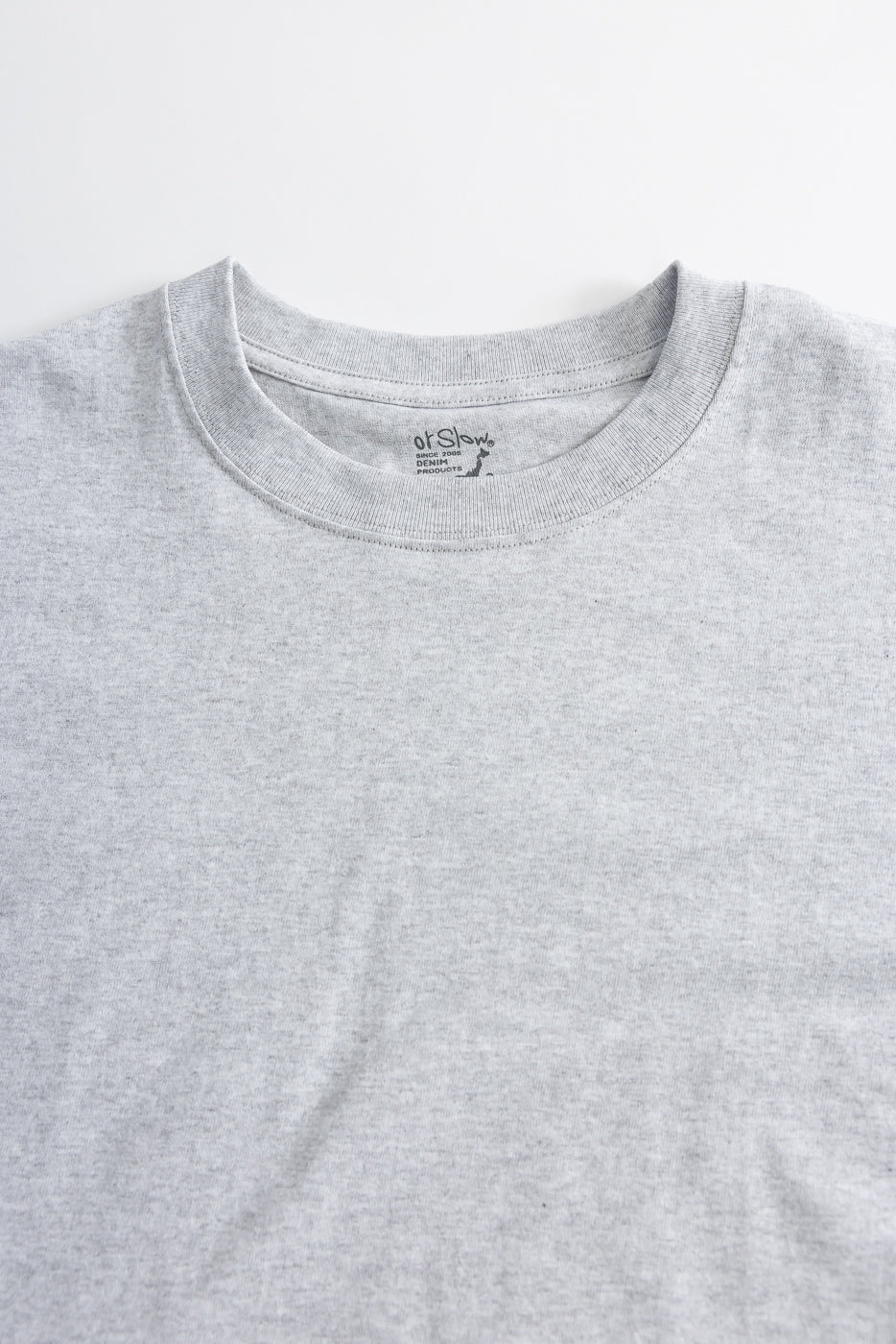 Close-up front view of heather grey crewneck t-shirt showing fabric texture, collar, and tag details.