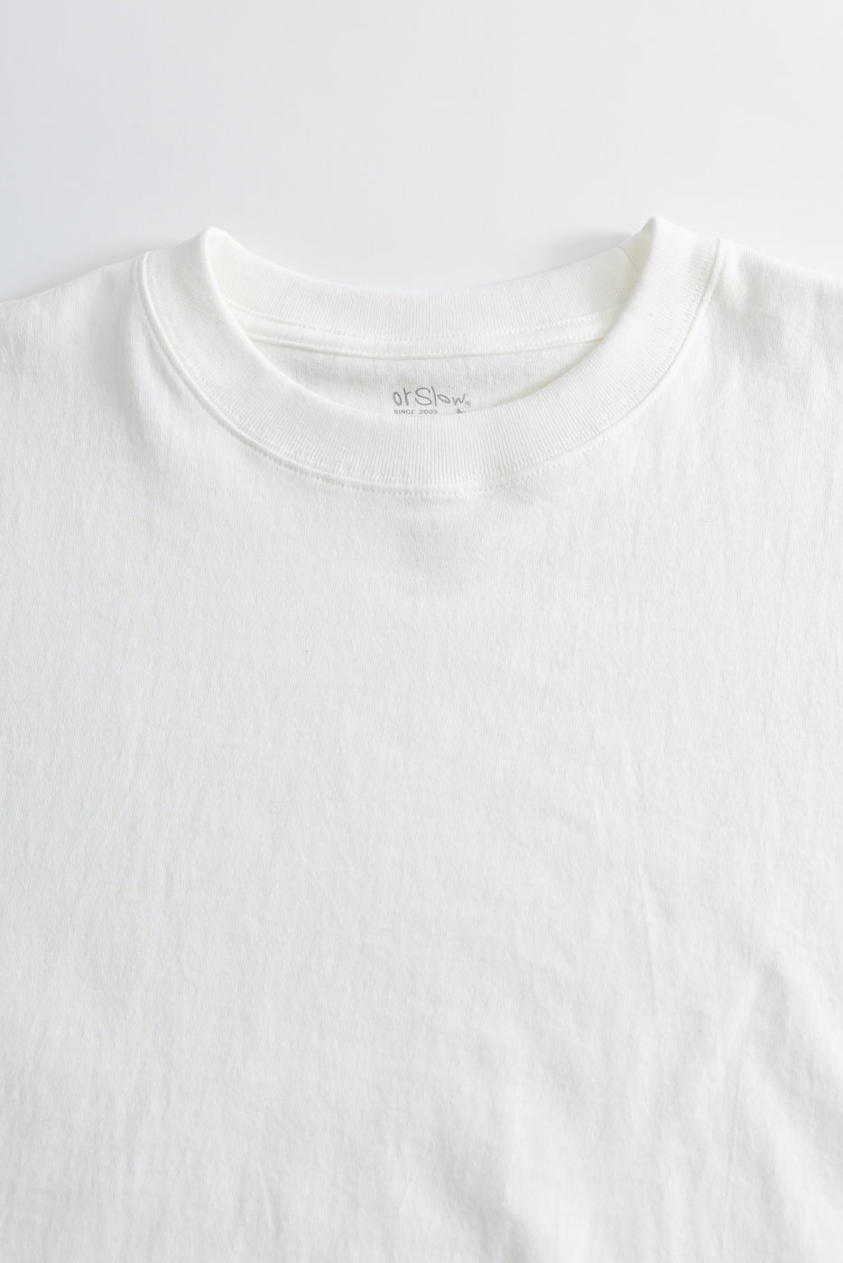Close-up of front upper section of white t-shirt showing ribbed crewneck collar and fabric texture.