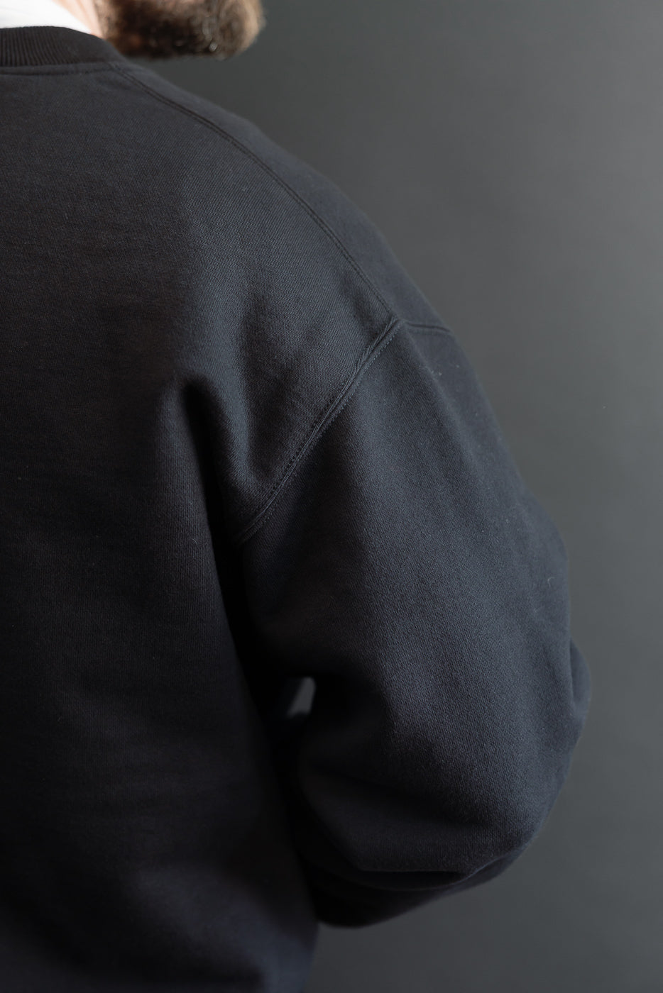 Close-up of back and shoulder of a navy sweatshirt on a male model, 5'9