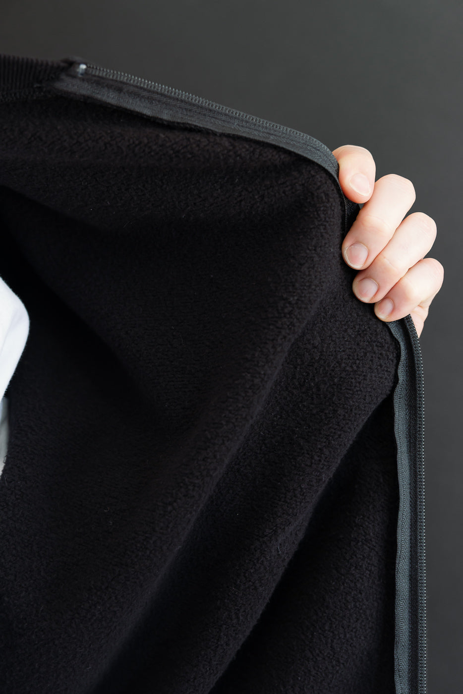 Close-up of the black fleece interior texture and side zipper of a garment.