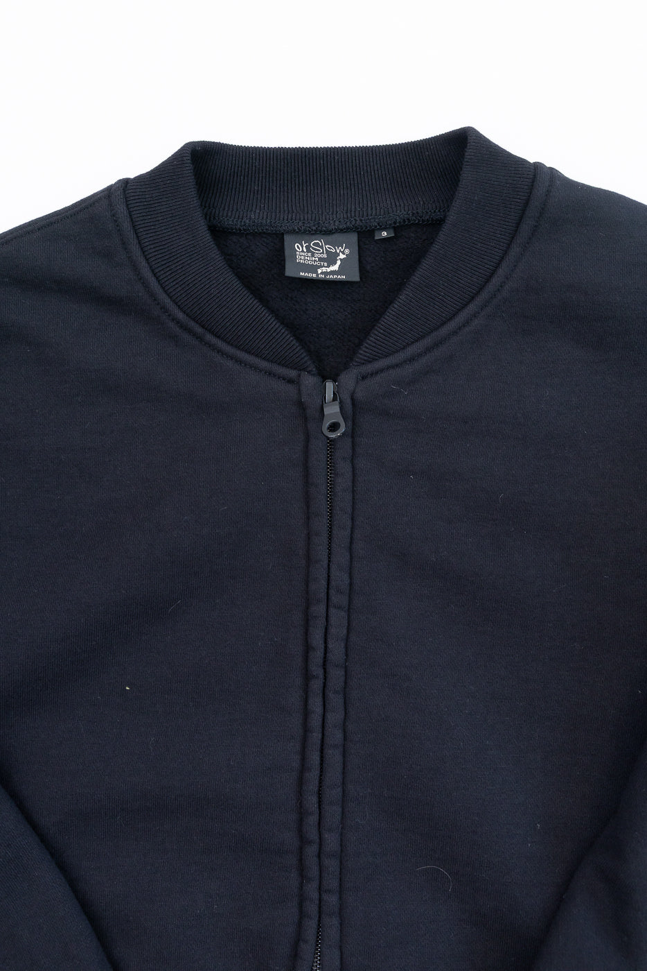 Close-up front view of the collar and zipper of a black sweatshirt with an OrSlow tag.