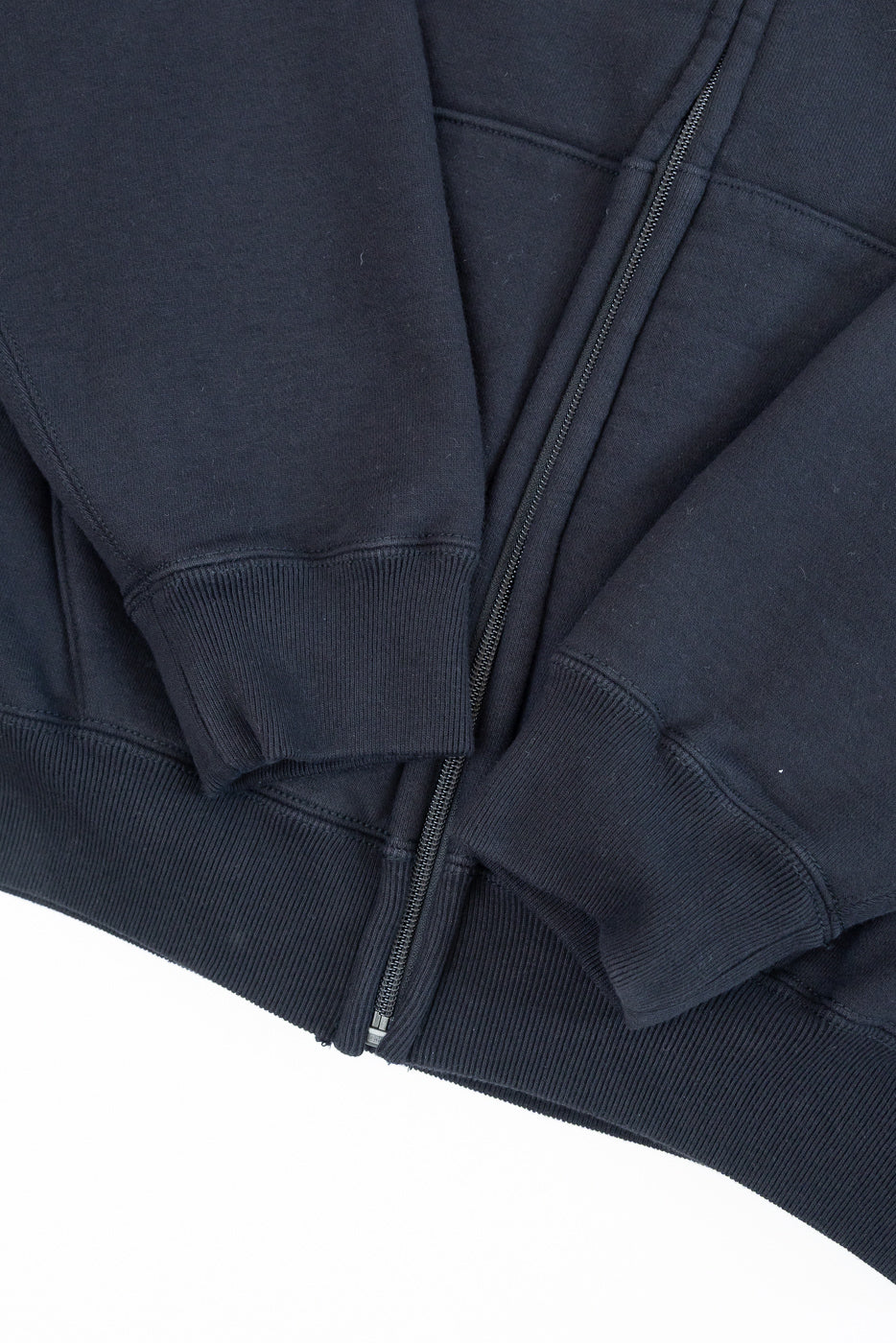 Close-up of the front hem and ribbed cuffs of a navy blue zip-up hoodie.