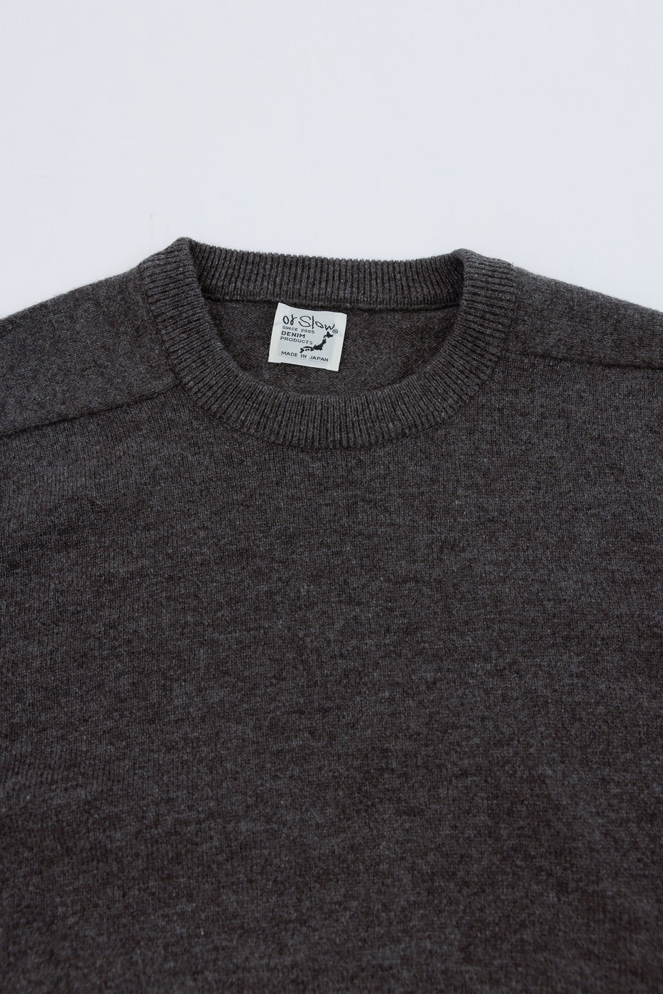 Close-up of the front neckline and tag of a charcoal grey knit sweater.