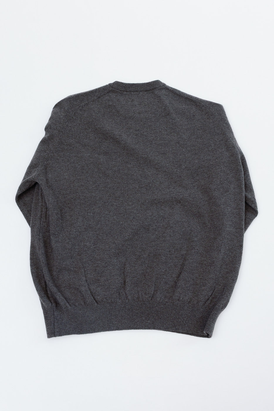 Flat lay of the back of a charcoal grey knit sweater.