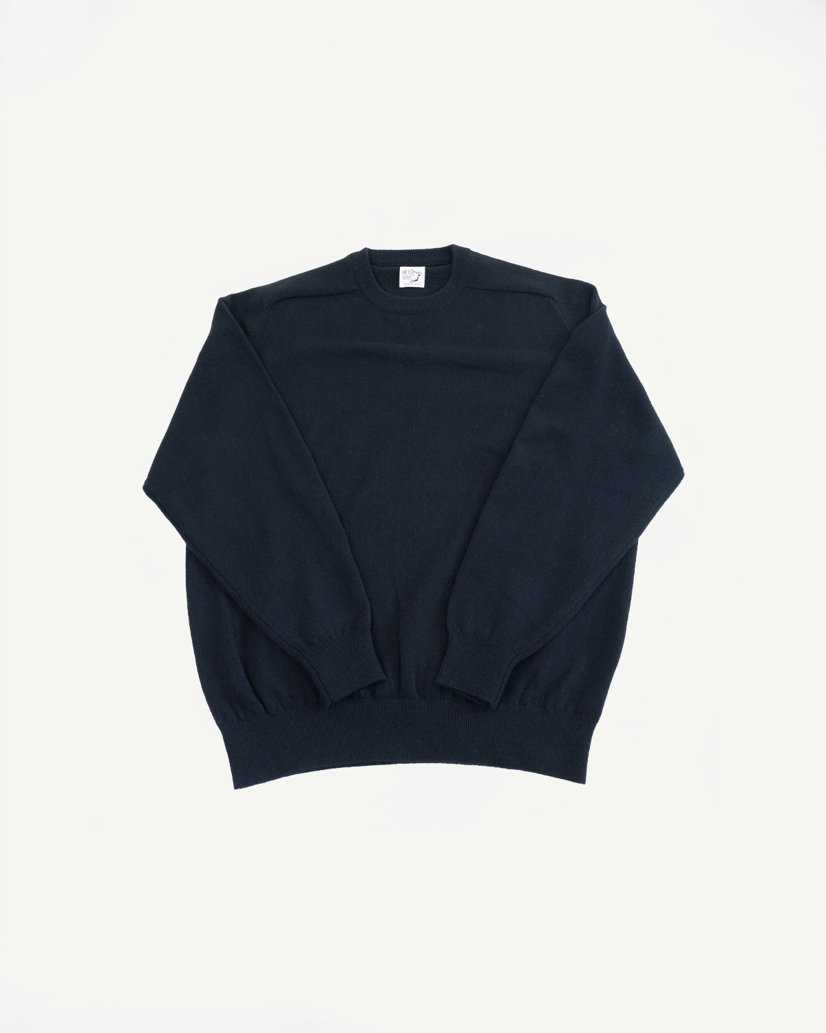 Flat lay front view of a navy blue crewneck knit sweater showing the collar and ribbed hem.