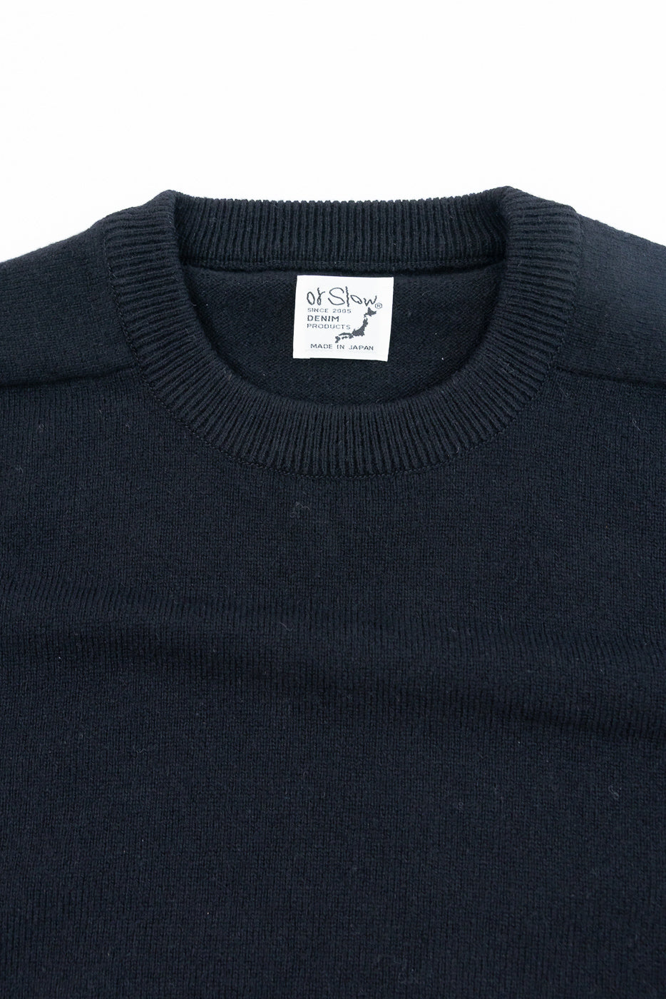 Close-up of the front neckline and tag of a navy blue knit sweater.