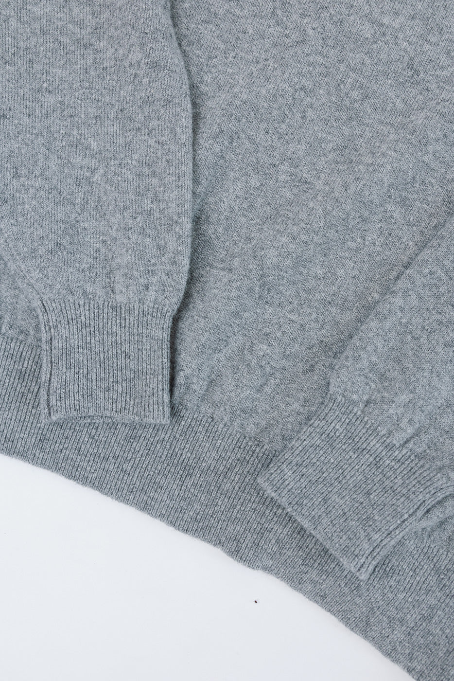Close-up of the ribbed cuffs and knit fabric texture on a grey sweater.