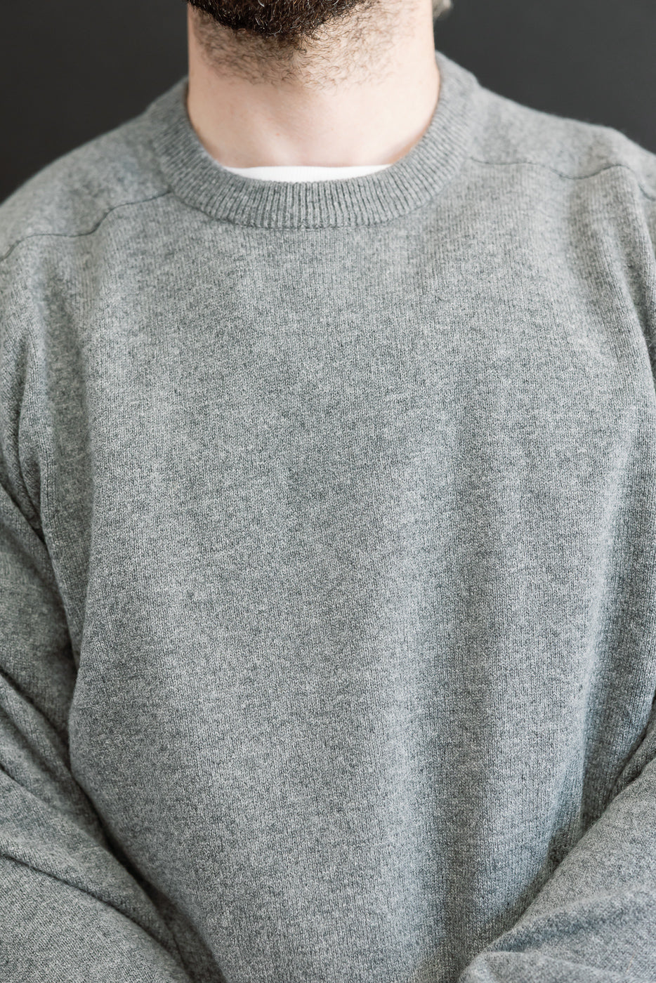 Close-up front view of a grey crewneck sweater on a male model, 5'9