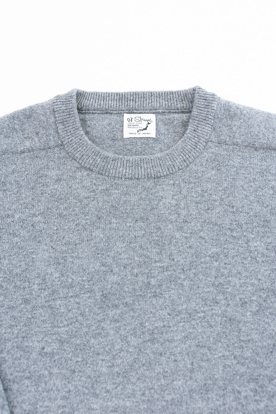 Close-up of the front neckline and interior tag of a grey knit sweater.