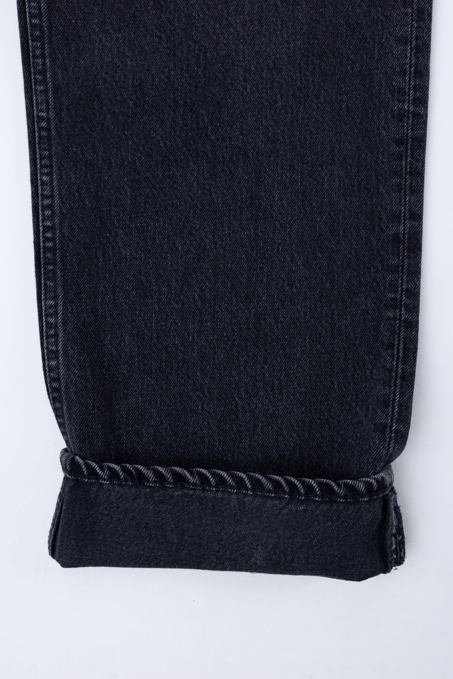 Close-up of the bottom hem and cuffed leg of black denim jeans, showing fabric texture.