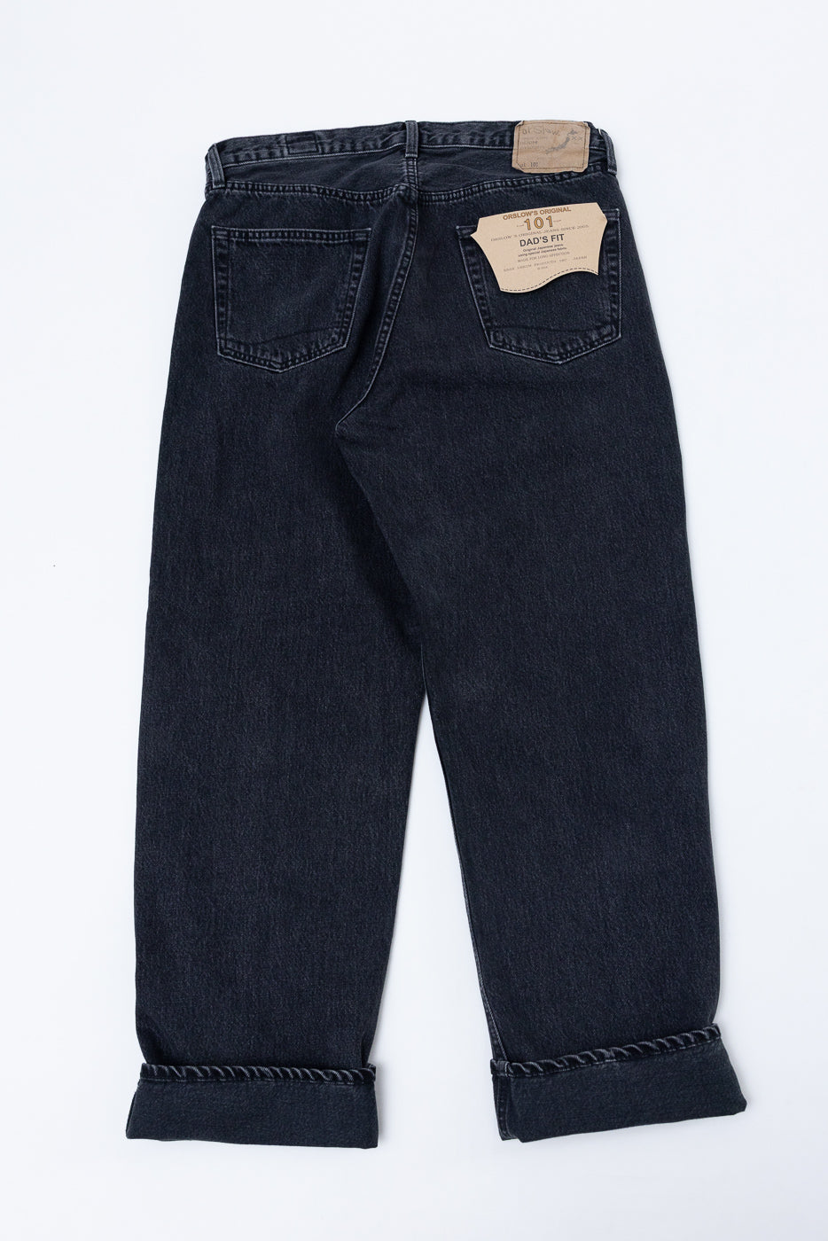 Back view flat lay of dark wash denim jeans with cuffed hems and a tan brand patch.