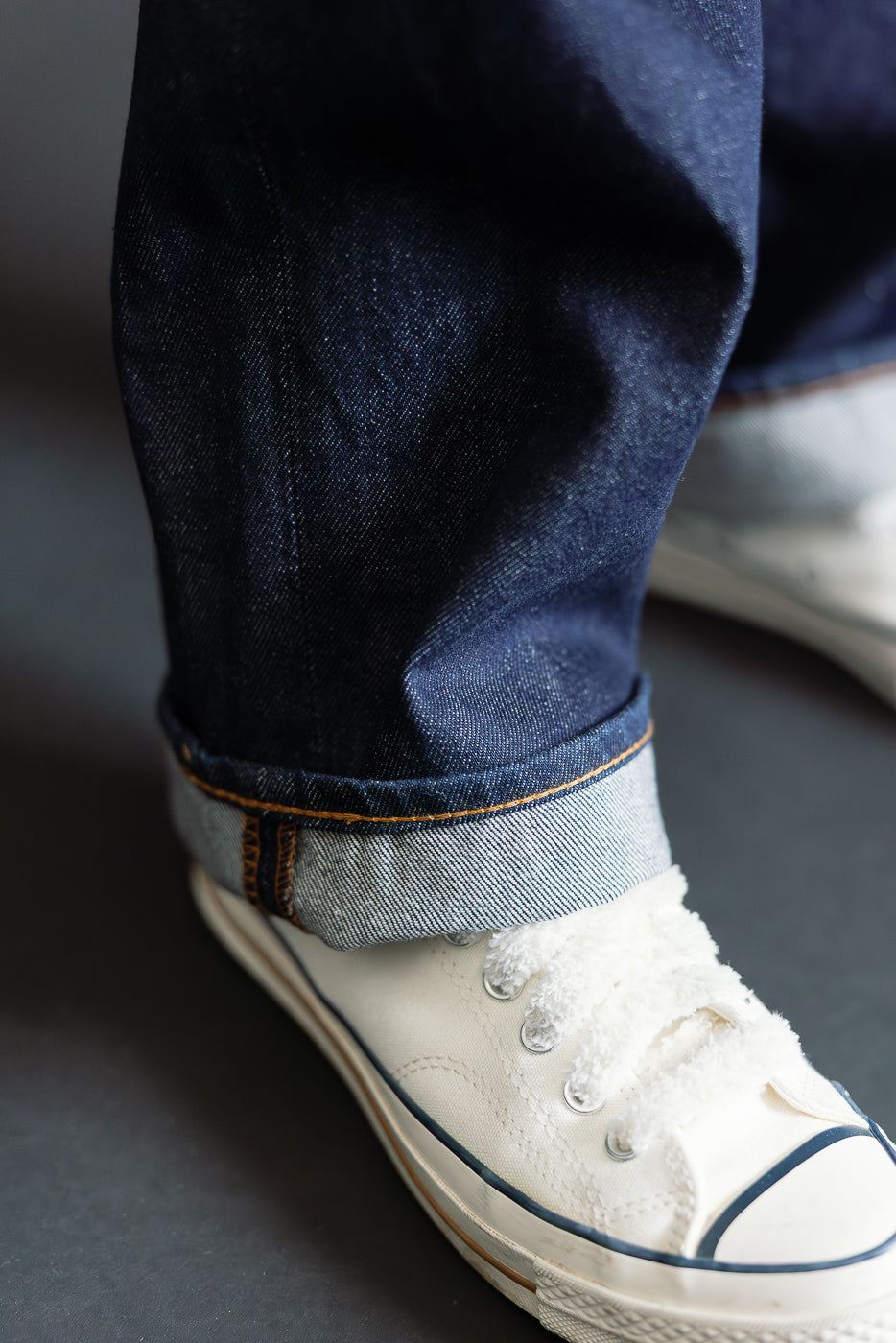 Close-up front view of cuffed Orslow Dad's Fit selvedge denim jeans hem and sneaker detail