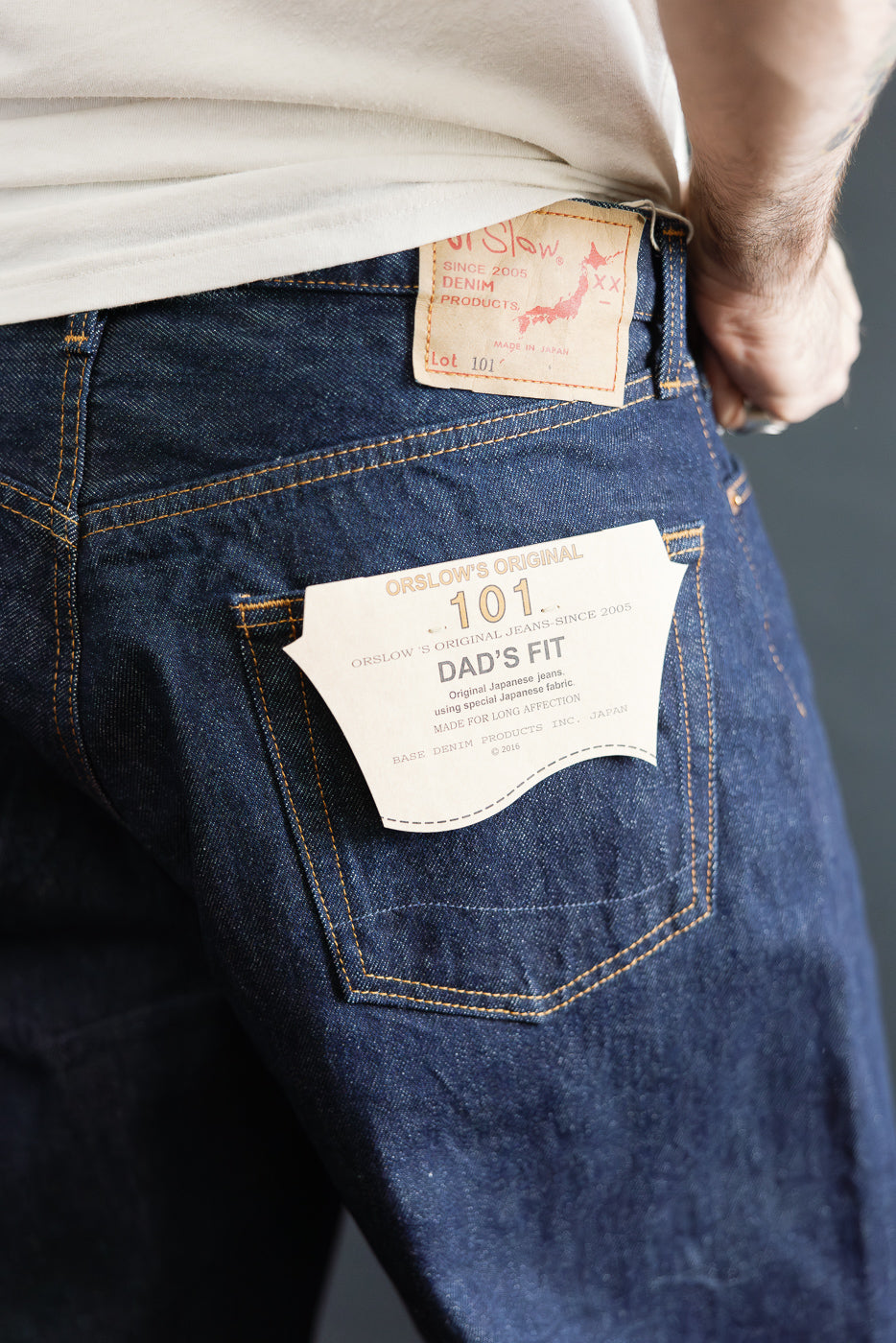 Close-up of men's orSlow Dad’s Fit denim jeans back pocket, leather patch and paper tag, worn by male model 5'9