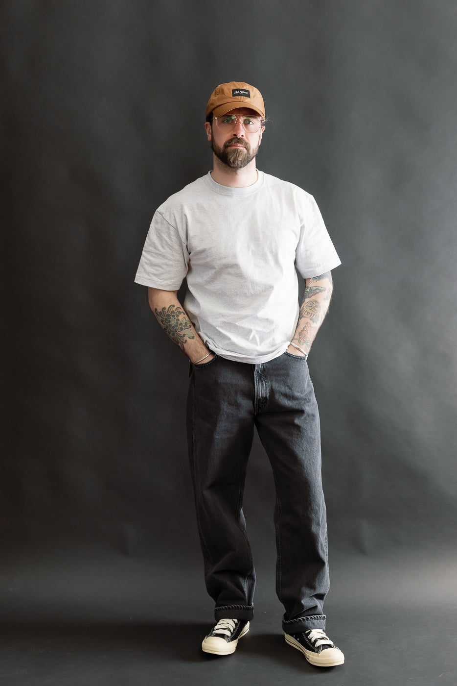 Man wearing 01-1010W-D61S - 101 Dad’s Fit Denim - 90s Black Stone, featuring relaxed fit black stone-washed jeans, classic five-pocket design, paired with a light gray T-shirt and sneakers.