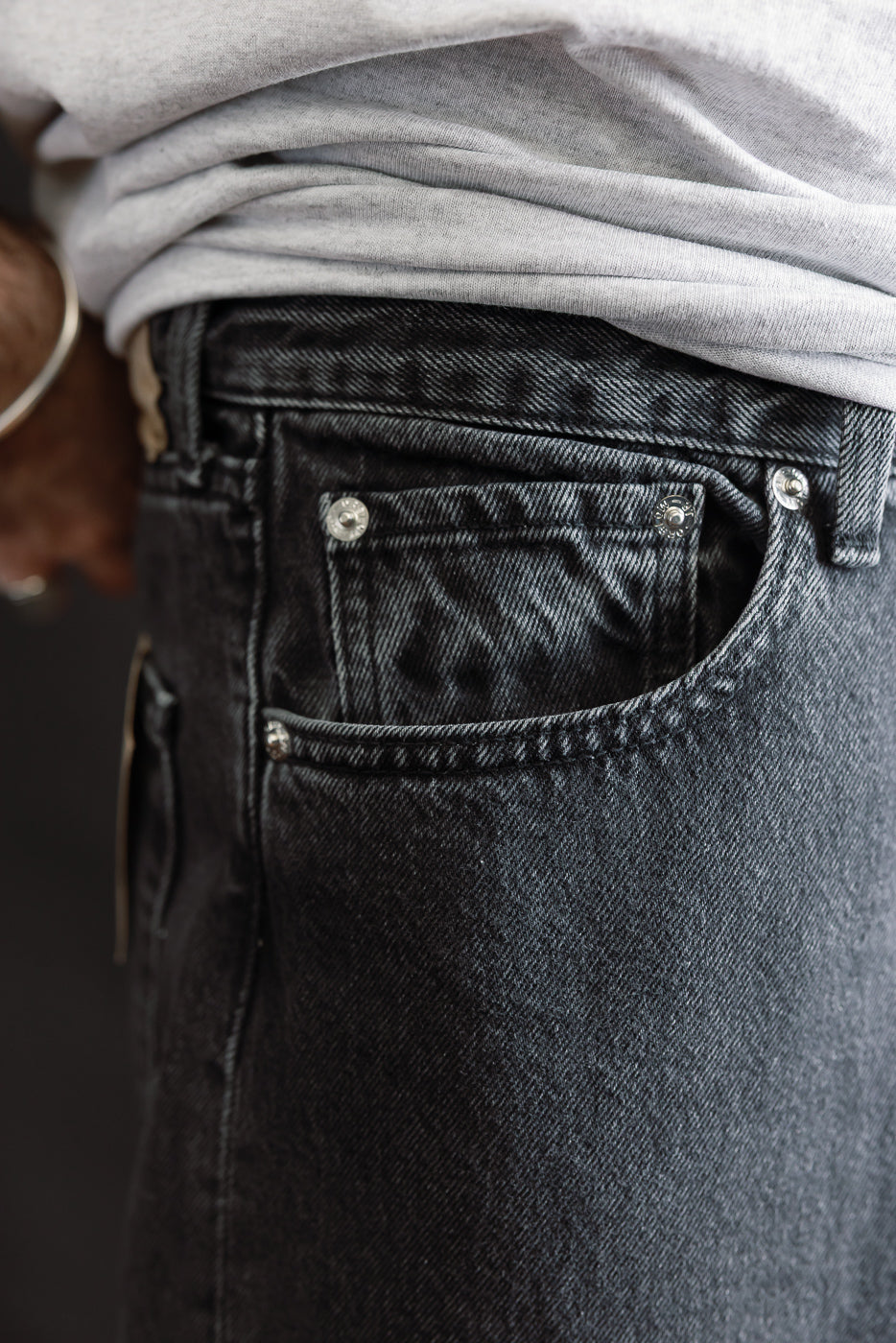 Close-up of 01-1010W-D61S - 101 Dad’s Fit Denim - 90s Black Stone, highlighting dark-washed denim details like rivets and coin pocket, paired with a light gray T-shirt, reflecting orSlow’s relaxed 90s-inspired style.