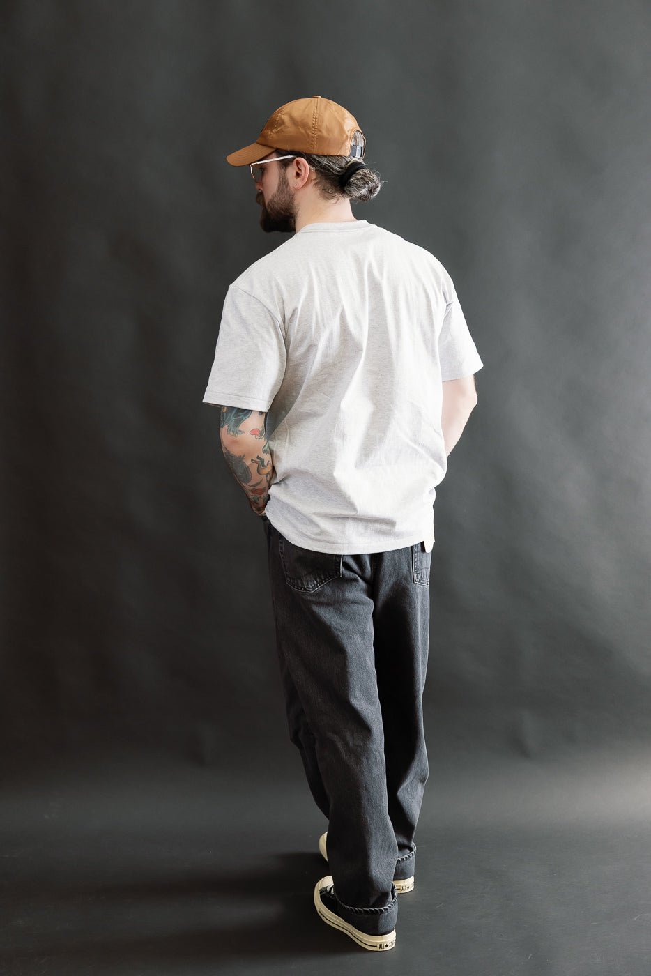 Man modeling 01-1010W-D61S - 101 Dad’s Fit Denim - 90s Black Stone, showcasing relaxed-fit, five-pocket black jeans with a stone-washed, faded gray look, styled with a casual t-shirt and sneakers.