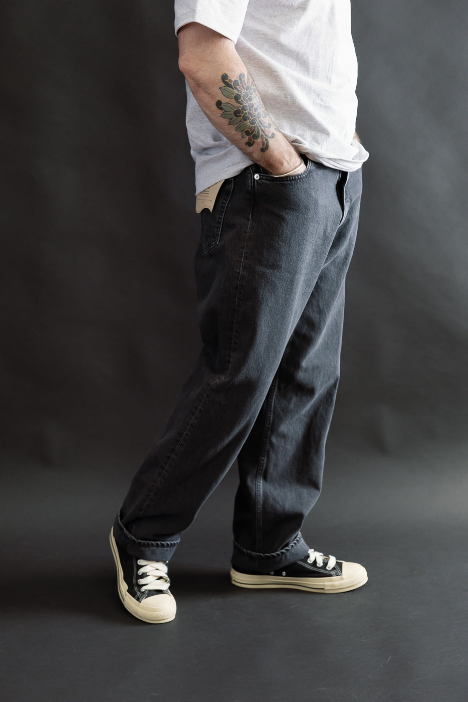 01-1010W-D61S - 101 Dad’s Fit Denim - 90s Black Stone features relaxed-fit, washed-black jeans with classic five-pocket construction, paired with black canvas sneakers, showcasing a vintage-inspired style.