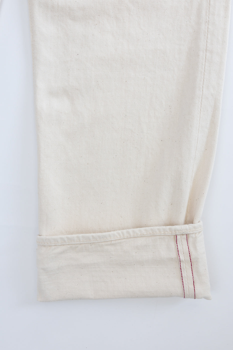 Close-up of the 01-1011-66 - Grand Dad's Fit Kinari Selvedge - Ecru trousers' cuff, highlighting the off-white selvedge denim with distinct red stitching, exemplifying orSlow's 1930s workwear-inspired craftsmanship.