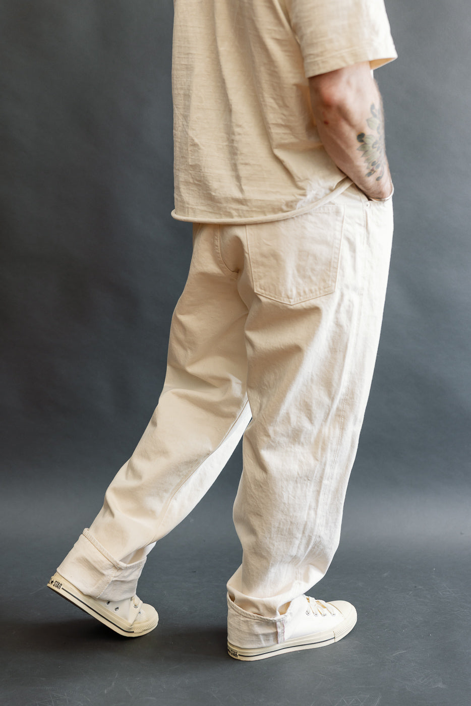 Model wearing orSlow's 01-1011-66 Grand Dad's Fit Kinari Selvedge trousers in ecru, featuring a relaxed straight leg, rolled cuffs, and classic workwear details, paired with white canvas sneakers.