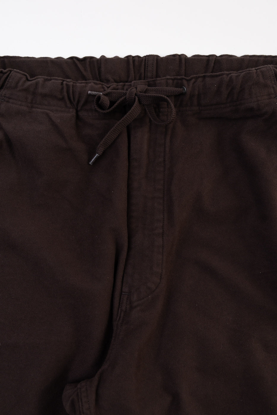 Close-up front view of brown drawstring waistband and fabric texture of casual trousers.
