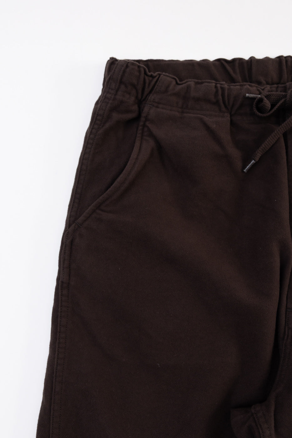 Close-up, front view of the waistband and pocket of brown fleece sweatpants.
