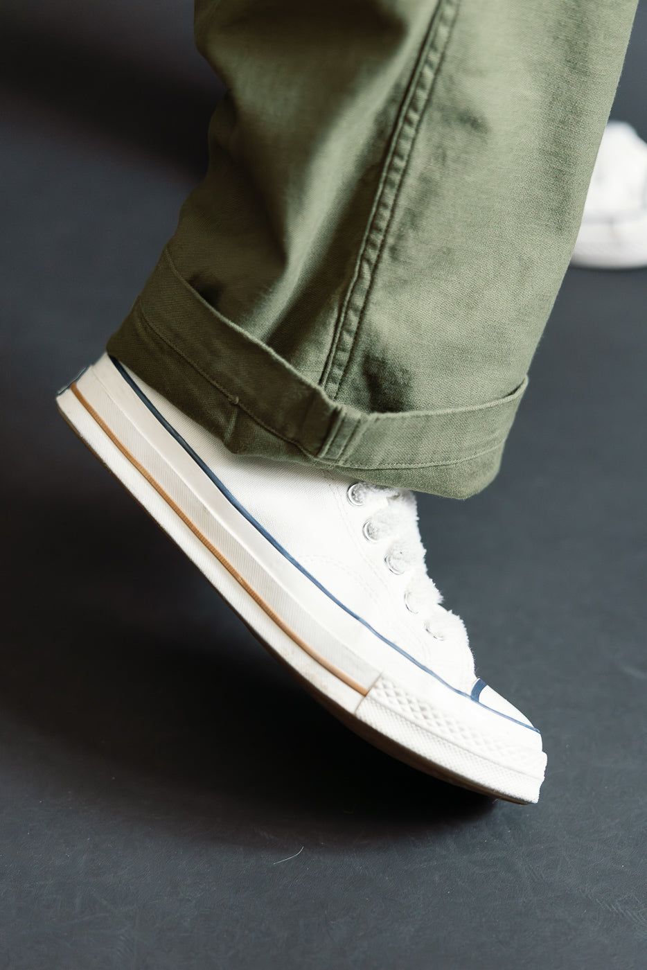 Close-up of dark olive wide fit orSlow New Yorker pants front hem on male model, 5'9