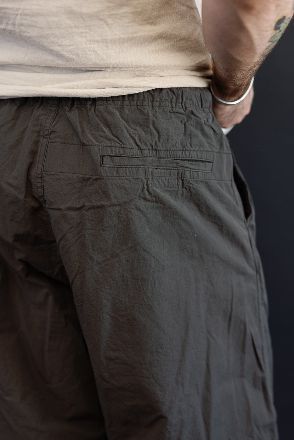 Close-up back view of dark gray casual shorts, showing rear pocket and fabric texture, worn by male model.
