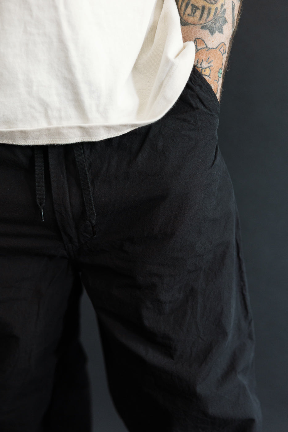 Close-up front view of black drawstring pants on male model, 5'9
