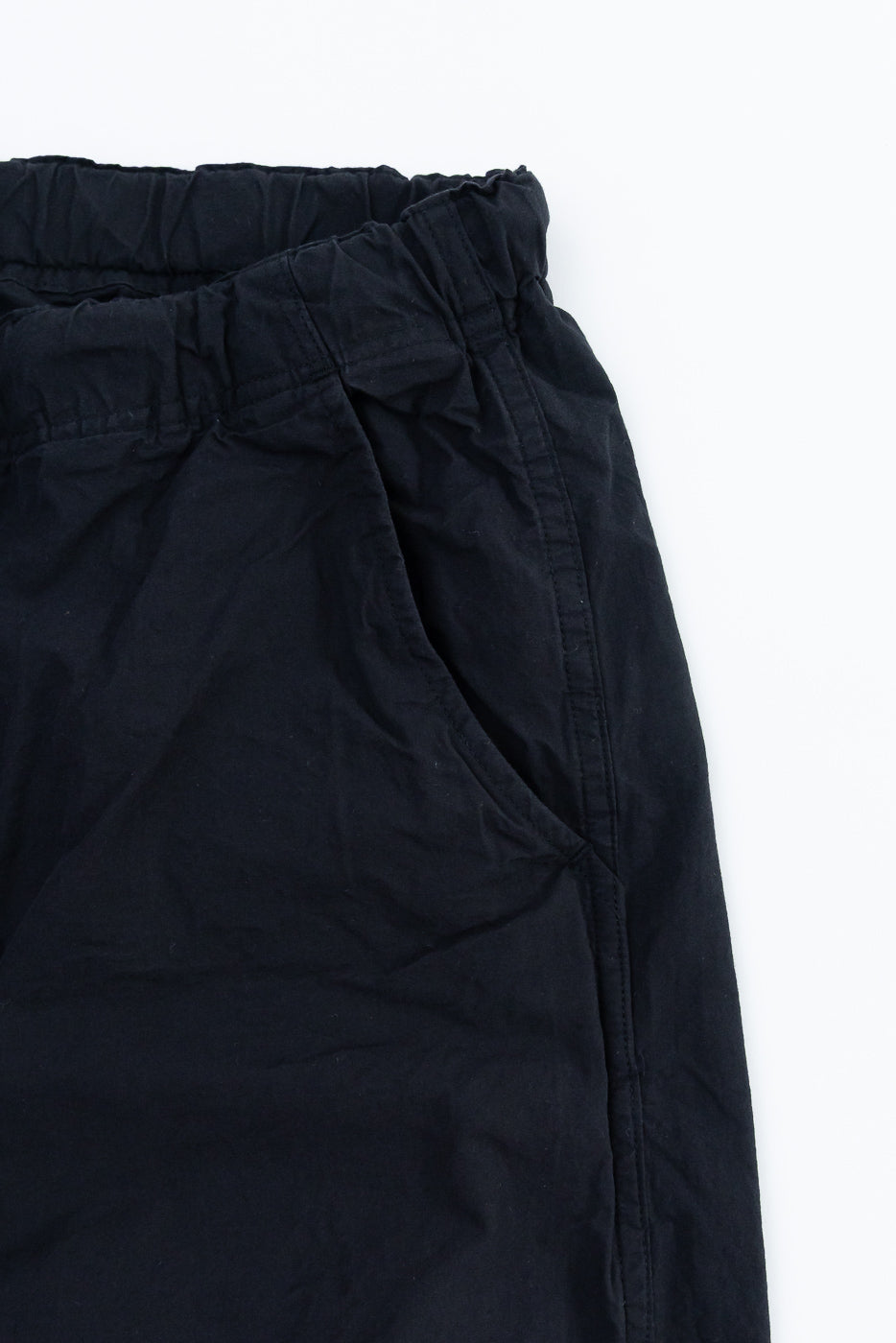 Close-up of black pants front, elastic waistband, and fabric texture