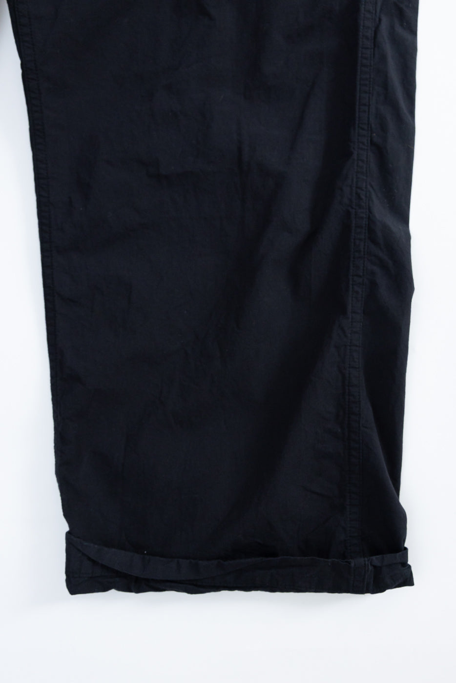 Close-up of black pants front, showing hem and fabric texture