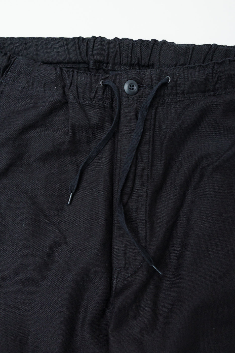 Close-up of orSlow New Yorker Pants front waistband in black, showing button, drawstring, and fabric texture.