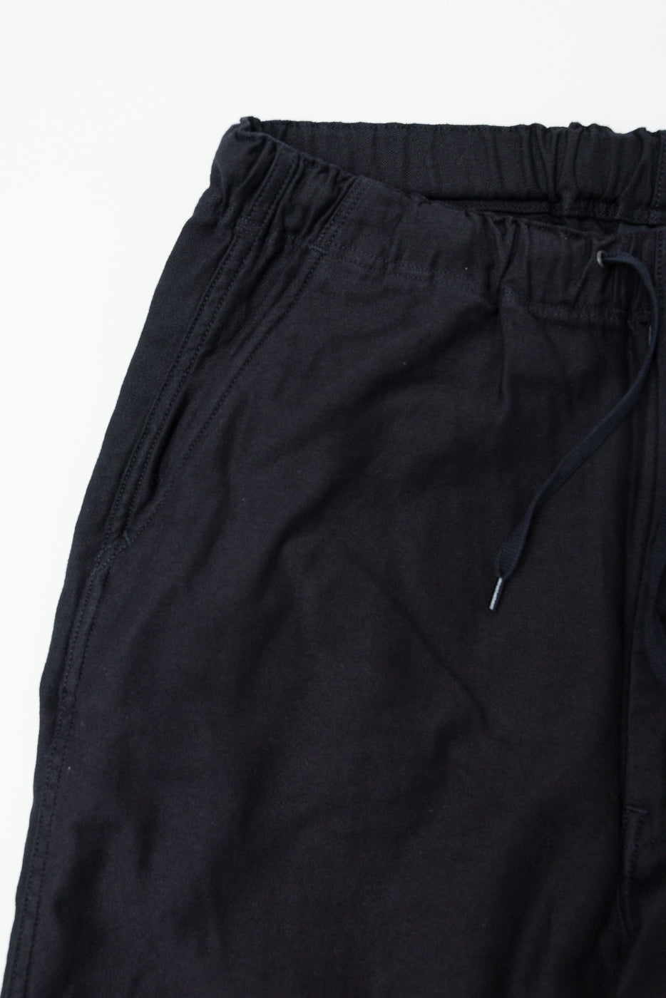 Close-up front detail of orSlow New Yorker Pants in black showing elastic waistband, pocket, and fabric texture.