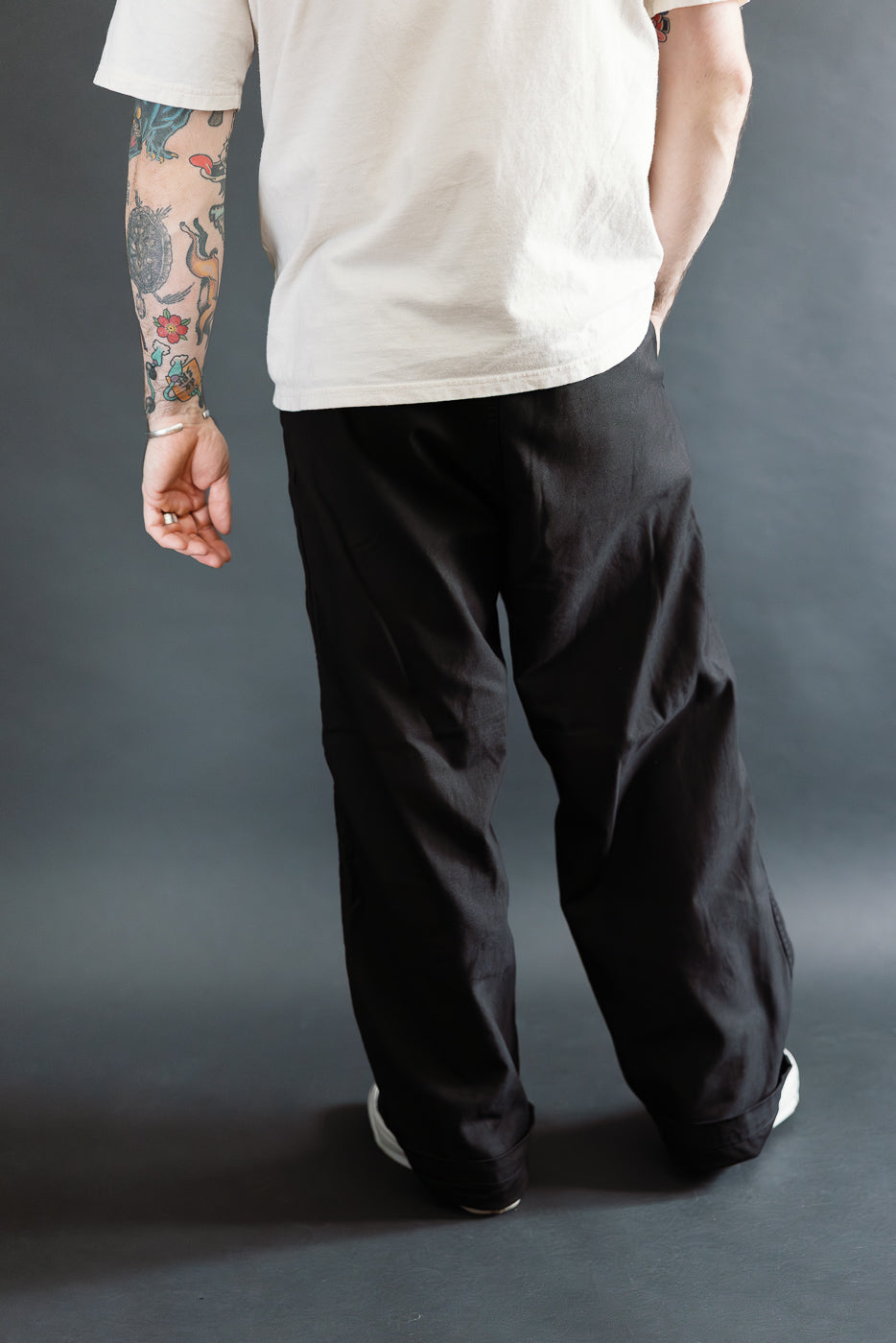 Back view close-up of black wide fit orSlow New Yorker pants on male model 5'9, 165lbs, athletic build