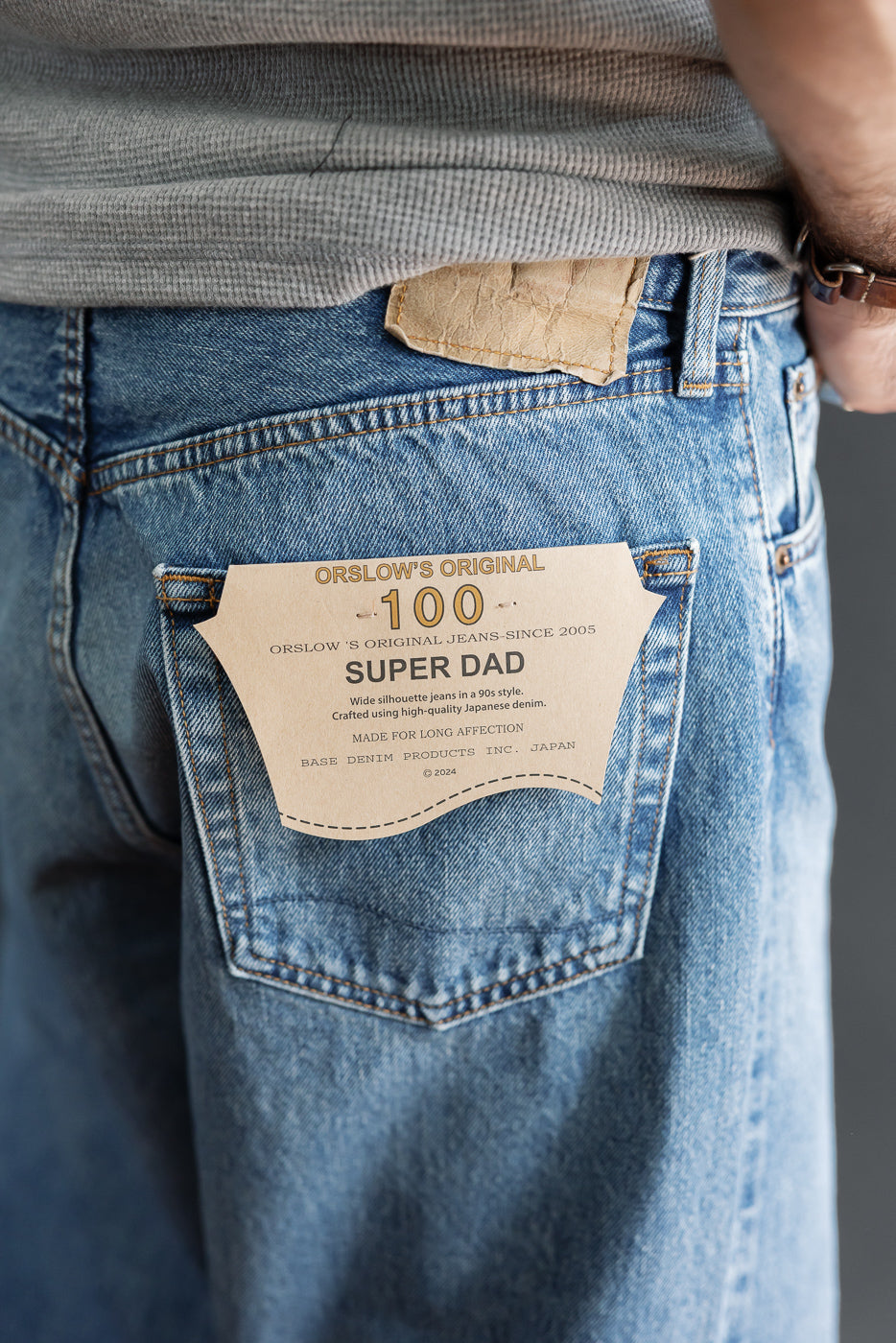 Close-up back view of light wash denim jeans showing the Orslow Super Dad leather patch.