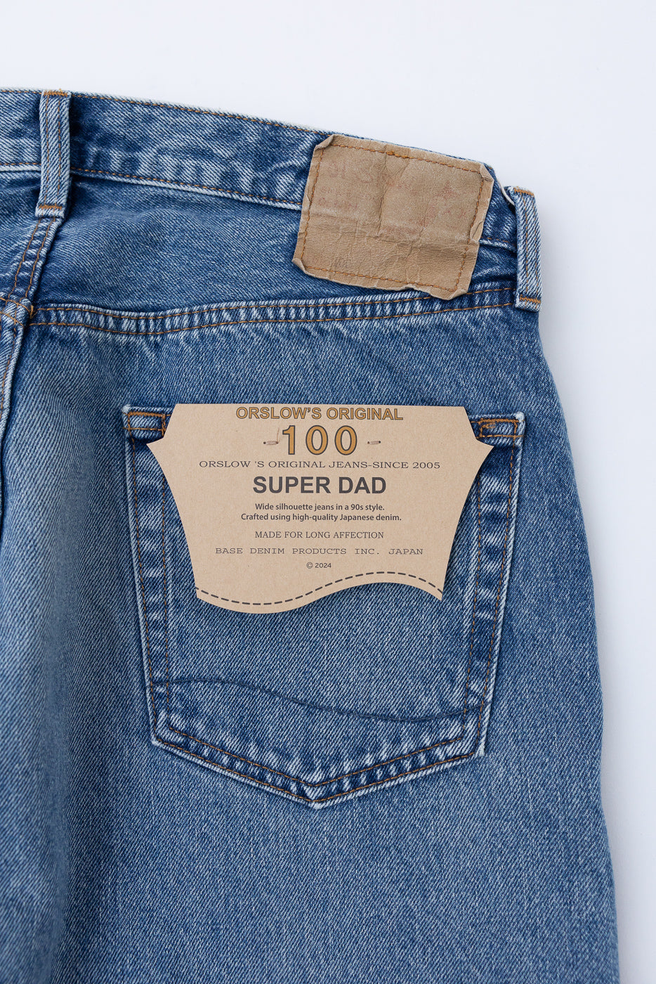 Close-up back view of blue denim jeans showing the Orslow Super Dad patch and waist label.