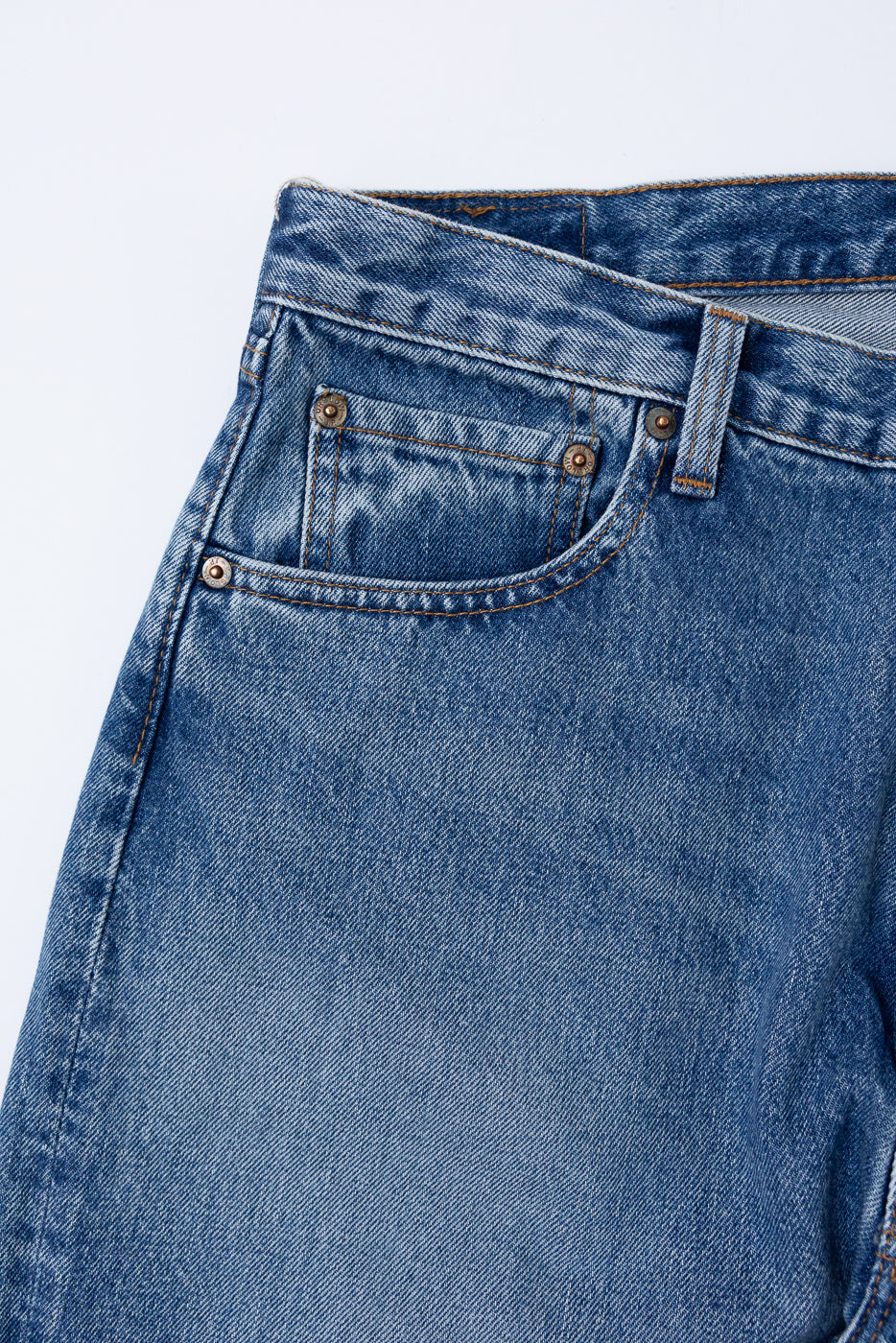 Close-up front view of blue denim jeans showing waistband, belt loops, and pocket detail.