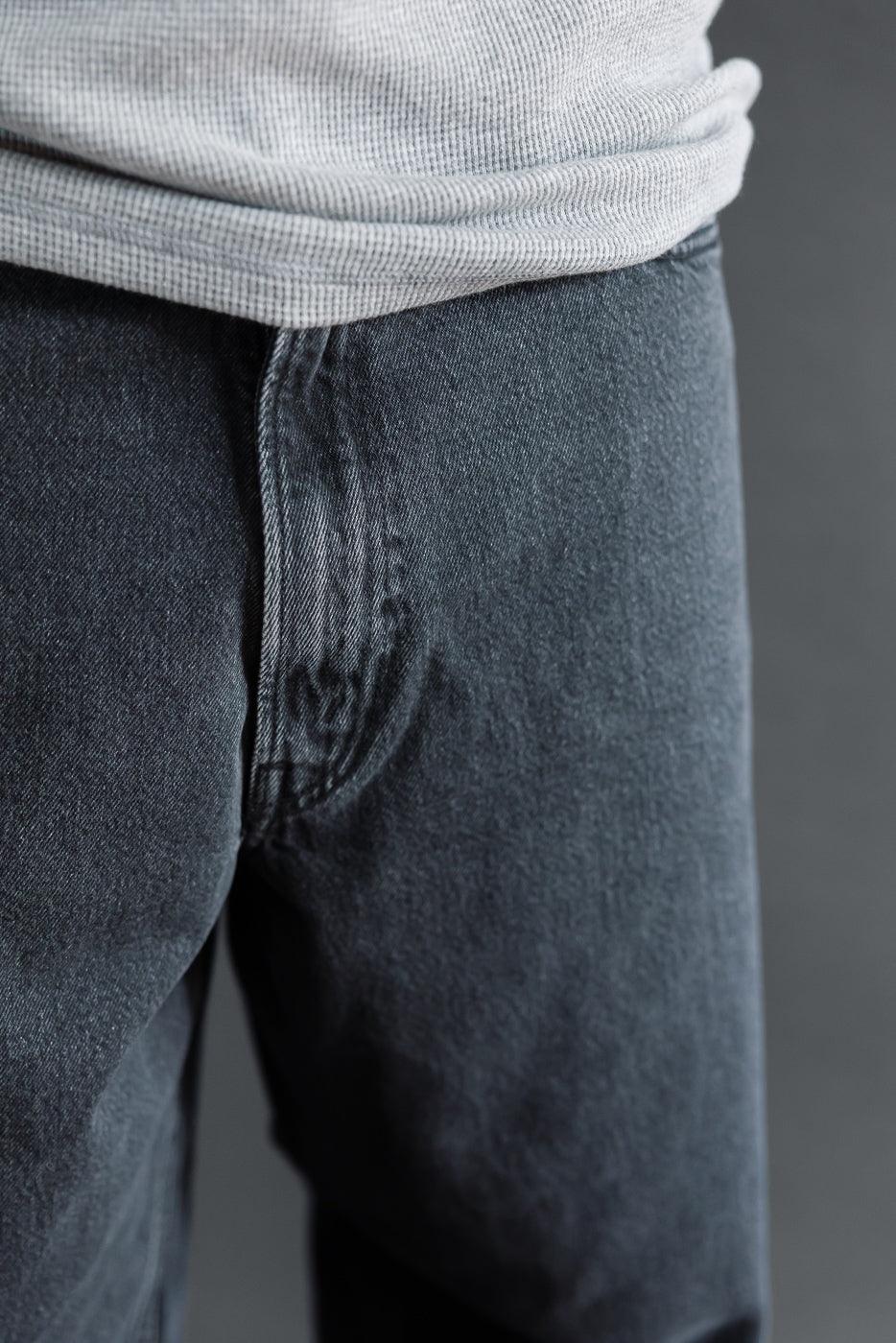 Close-up front view of grey denim jeans on a male model, 5'9