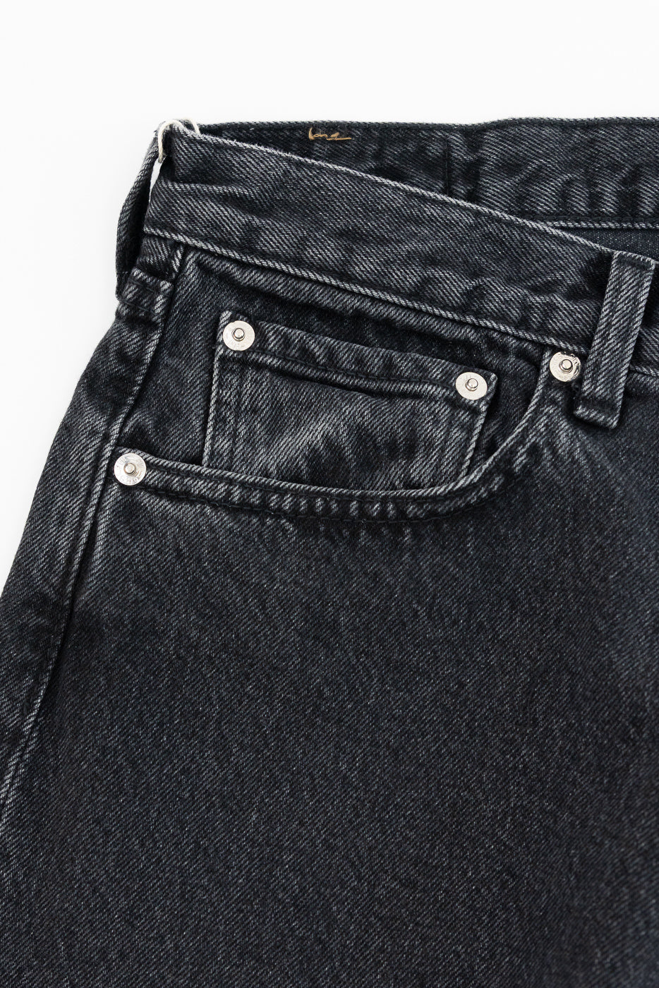 Close-up of black denim jeans back pocket with silver rivets and fabric texture detail
