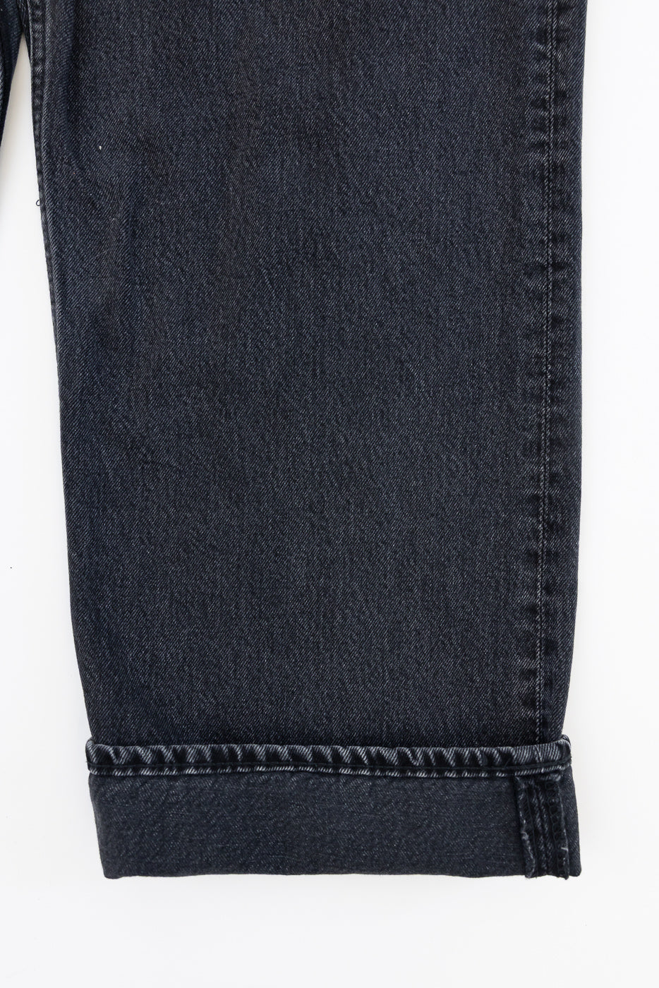 Close-up of black selvedge jeans hem, showcasing detailed stitching and fabric texture