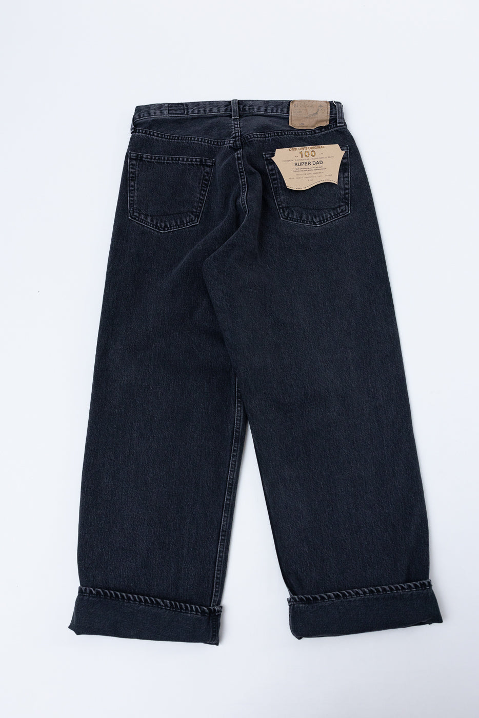Back view flat lay of dark denim Super Dad jeans with cuffed hems and a brand patch.