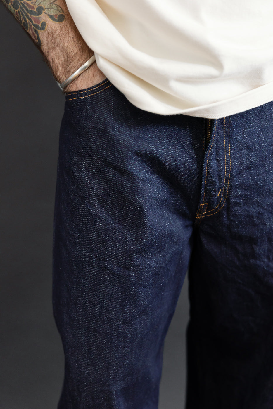 Close-up front view of dark indigo selvedge denim jeans worn by a male model.